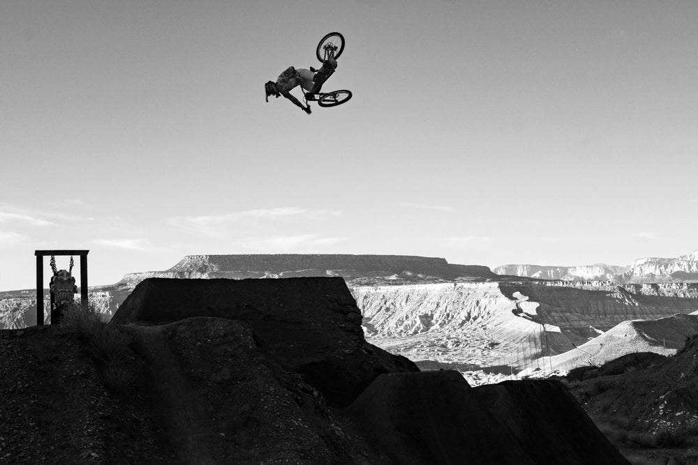 Biker performing a stunt in mid-air over a canyon landscape