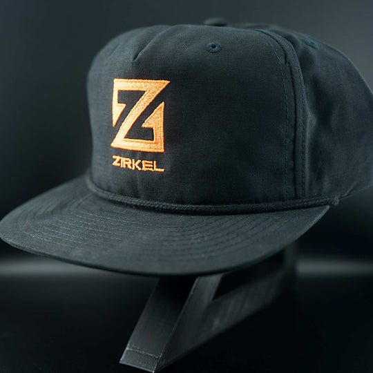 Black cap with orange Zirkel logo on a dark background