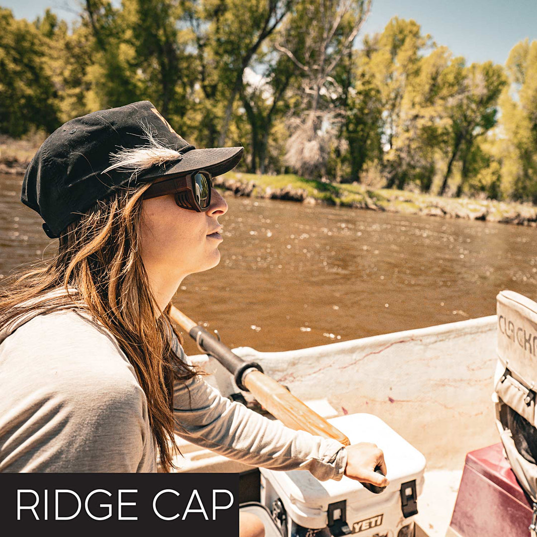 Person in a boat on a river wearing a Zirkel Ridge Cap and Zirkel Optics sunglasses, with 'RIDGE CAP' text.
