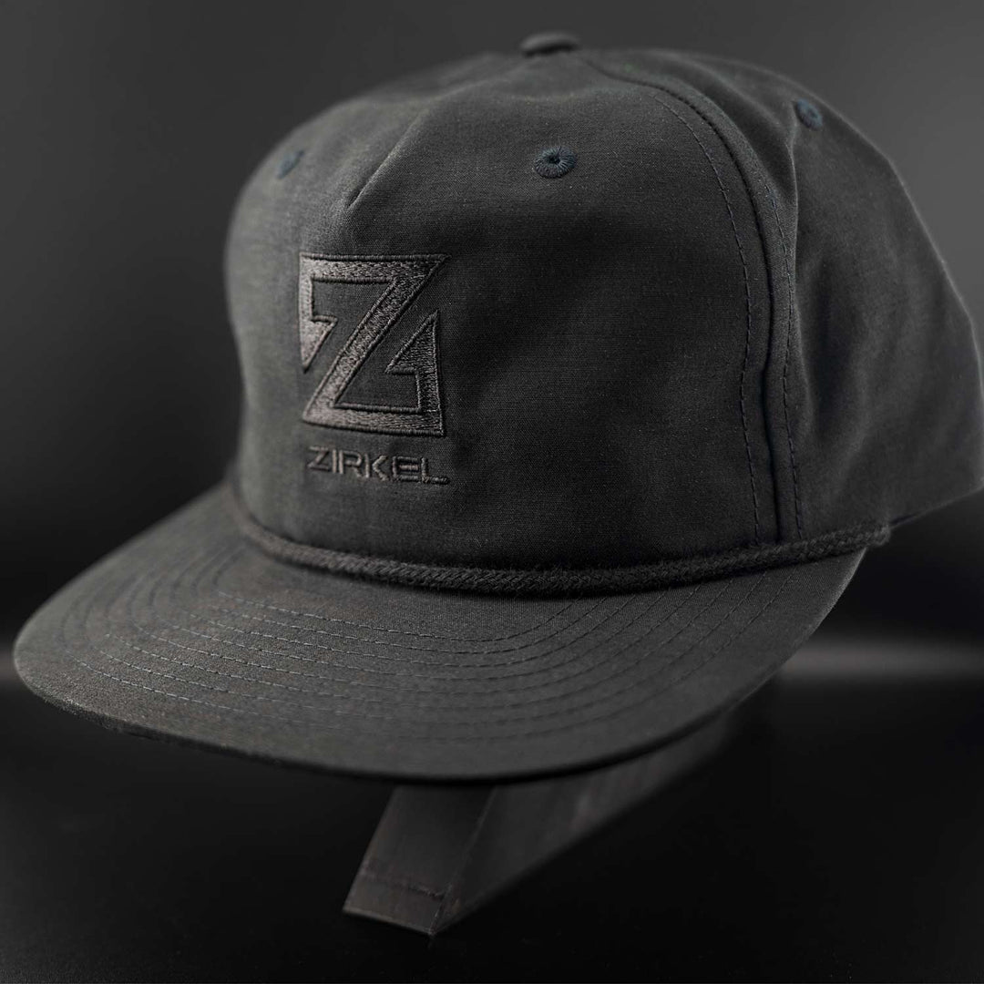 Black cap with a black Zirkel logo on a dark background